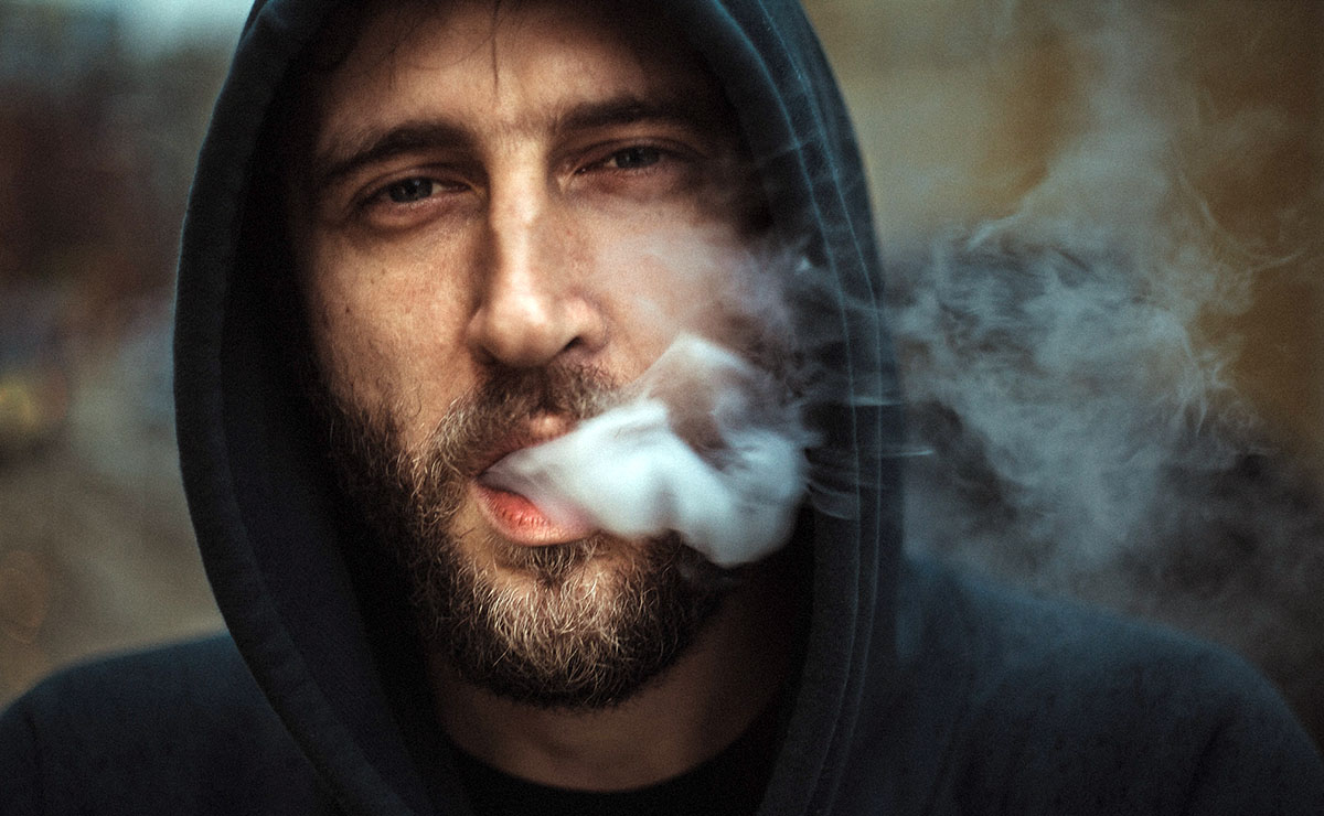 Rökande man med huva. Foto: Vadim Kaipov. Licens: Unsplash.com