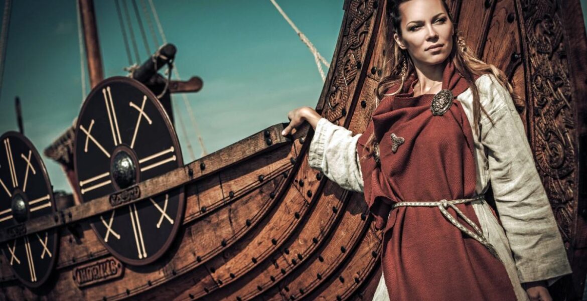 Rekonstruktion av vikingakvinna vid en vikingabåt | Depositphotos.com