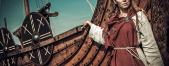 Rekonstruktion av vikingakvinna vid en vikingabåt | Depositphotos.com