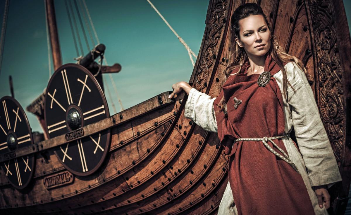 Rekonstruktion av vikingakvinna vid en vikingabåt | Depositphotos.com